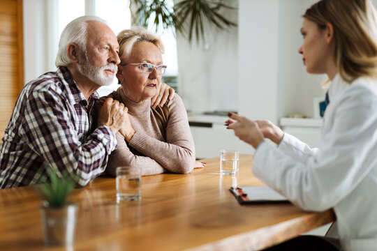 Worried mature couple talking to their doctor during her home visit