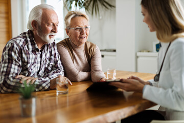 Obraz premium Mature couple talking to their doctor during her home visit