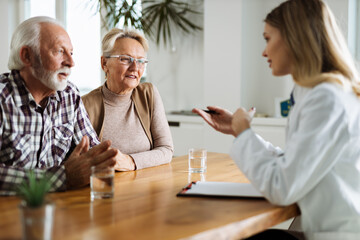Mature couple talking to their doctor during her home visit - obrazy, fototapety, plakaty