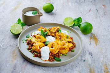 Traditional Oriental manti dumplings with spicy minced meat and yogurt served as close-up on a Nordic design plate