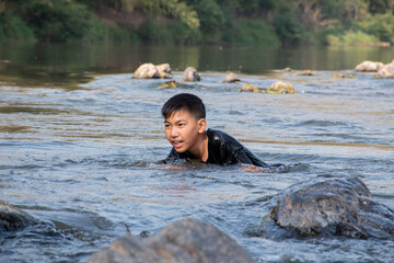 Asian boys are swimming and diving in the river happily, chilhood and summer vacation concept, in motion.