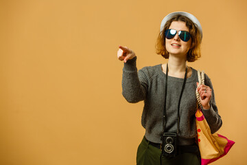 Traveler tourist woman 20s point index finger isolated on yellow orange background. Passenger traveling abroad on weekends getaway. Air flight journey concept