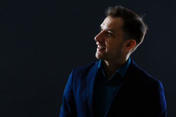 Fototapeta premium Portrait shot of a middle aged businessman wearing suit while standing at dark background.