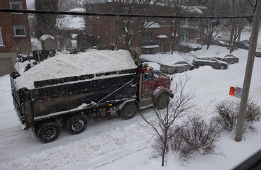 Camion de neige rouge et noir rempli de neige sur rue secondaire