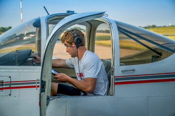 Teenage boy preparing to fly small airplane - obrazy, fototapety, plakaty