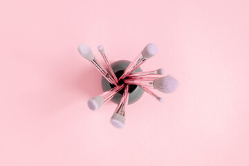 Makeup brushes on pink background. Flat lay, top view, copy space