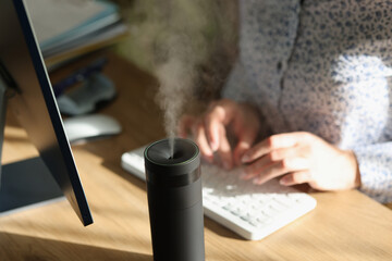 Modern air humidifier device on office desktop close-up.