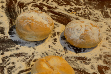 loaves of freshly baked bread with white flour on the counter of the bakery