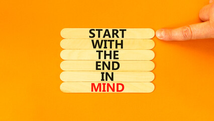 Start in end of mind symbol. Concept words Start with the end in mind on wooden stick. Beautiful orange table orange background. Businessman hand. Business start in end of mind concept. Copy space.