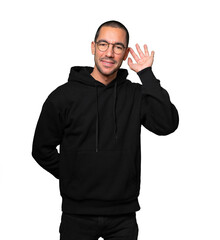 Fototapeta premium Happy young man smiling and making a gesture of trying to hear something
