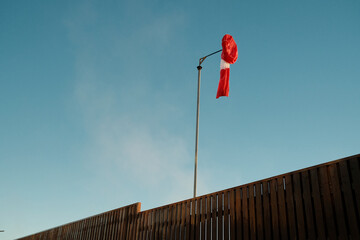 Tall pole with wind sleeve near fence