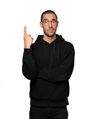 Fototapeta premium Hesitant young man pointing up with his finger