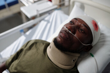 Sick military man with bleeding head injury lying on bed in hospital