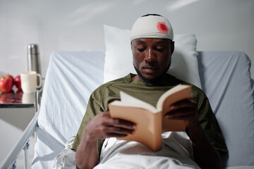 Sick military man reading good book when spending time in hospital