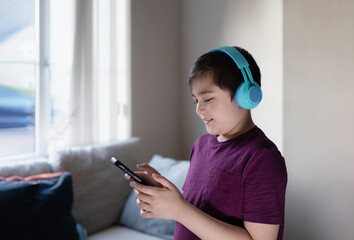 Primary school Kid using mobile phone searching information on internet for homework,Child wearing headphone studying online with teacher,Home schooling,E-learning education,Children with technology