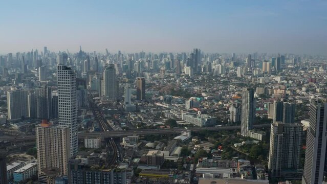 Aerial view of city skyline of Bangkok, cityscape with modern buildings and skyscrapers with clear blue sky behind them - landscape panorama of Thailand from above, Southeast Asia