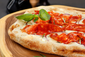 Crispy Gourmet Pepperoni Pizza with salami and basil leaves on wooden board. Close up