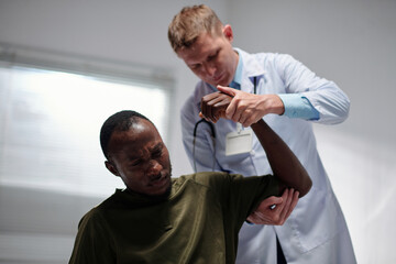 Doctor examining dislocated arm of military man