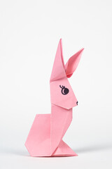 A pink origami rabbit on a white background. Crafts for Easter, fold from paper, do it yourself
