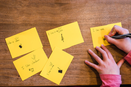 Above-view Of Hands Of Child Drawing With Pen On Cards