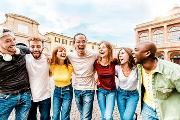 Group of lively young people laughing happily while walking together in the city - Smiling...