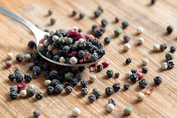 Dried round peppers on a spoon. Different peppercorns on a spoon