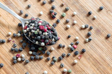 Dried round peppers on a spoon. Different peppercorns on a spoon