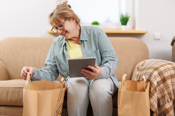 Ordering lunch or dinner home delivery service, adult caucasian woman unpacks eco package with salads in disposable tableware, ordering food in the kitchen, restaurant delivery concept