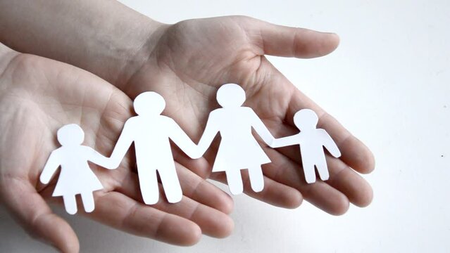 Close up hands of father, mother and daughters protecting family paper cutout. Hands of family with paper cutting and shaped symbol stone. Unity, insurance and love concept.