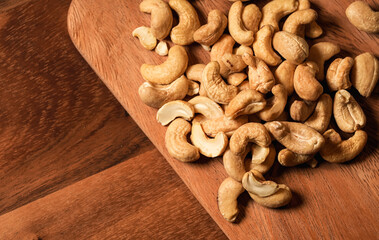 Detail view of cashew nuts from above. Close up photo with cashew on a wooden plate.