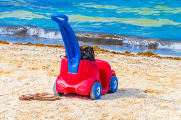 Red and blue toy car on the beach in Playa del Carmen Mexico.