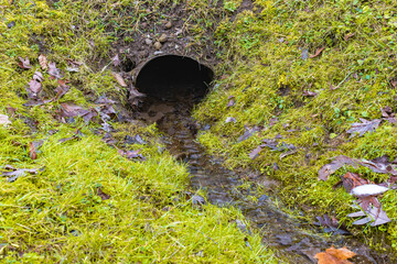 Sewer pipe with water flowing on cold day.