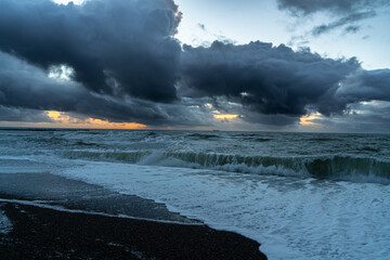 Panoramic view of Baltic sea from sandy shore, sand dunes. Dramatic sky with glowing clouds, sunbeams. Denmark