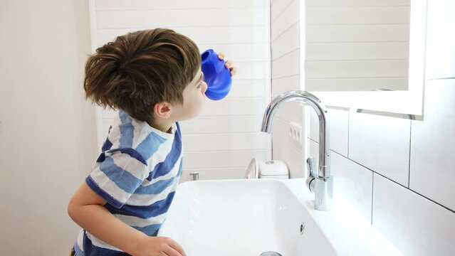 Nasal irrigation. Kid making nasal wash with saline. A young child boy uses the Neti Pot to treat runny nose. Nasal lavage. An Irrigation can. Sinus problem. Nasal allergies. Home bathroom background.