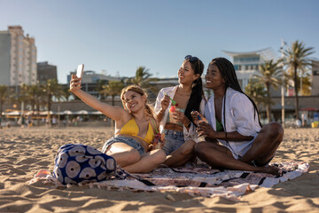 three diverse female friends make selfie on the beach on a sunny day, summer vacation
