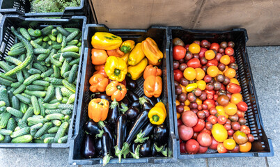 Cucumbers, peppers, eggplants and tomatoes in plastic boxes at a market