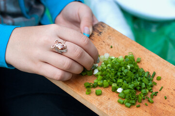 Female hands on dostochke with green chopped onions