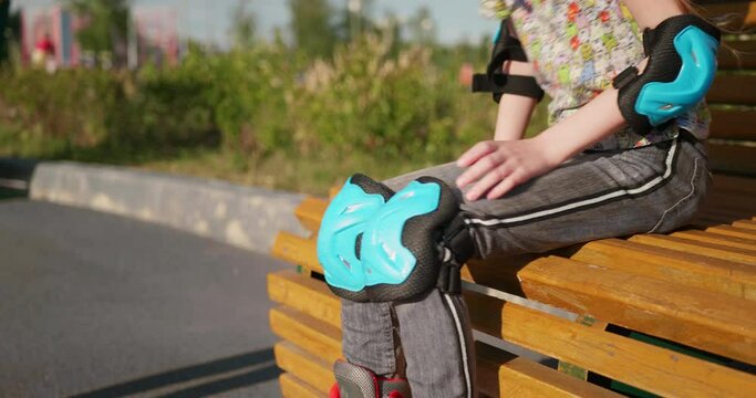 An unrecognizable mother helps her child put on knee pads for roller skating
