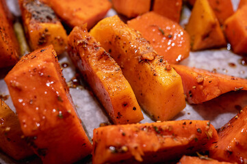 Roasted pumpkin on a light parchment background. Close up view, selective focus. Healthy food