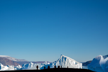 Silhouette of people with icebergs in the background
