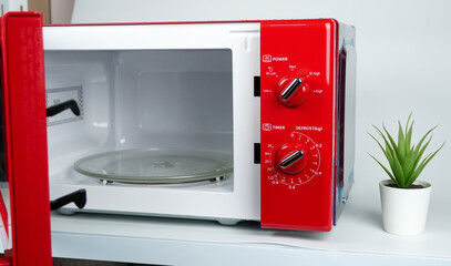 An open red microwave placed on the table.                        