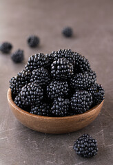 Fresh ripe blackberries in a wooden bowl on a brown background