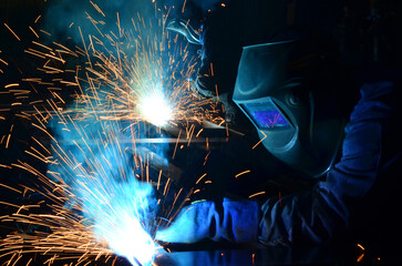 Workers wearing industrial uniforms and Welded Iron Mask at Steel welding plants, industrial safety first	

