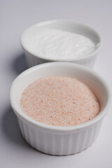 Raw whole dried pink Himalayan salt in a container on white 