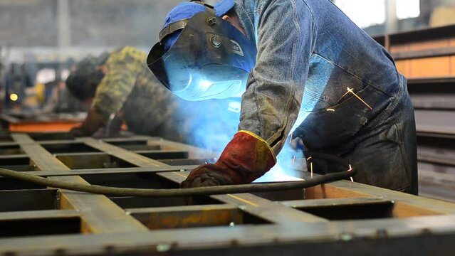 Workers wearing industrial uniforms and Welded Iron Mask at Steel welding plants, industrial safety first	
