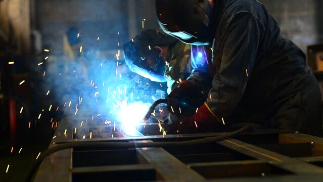 Workers wearing industrial uniforms and Welded Iron Mask at Steel welding plants, industrial safety first	
