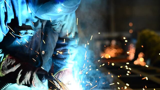 Workers wearing industrial uniforms and Welded Iron Mask at Steel welding plants, industrial safety first	
