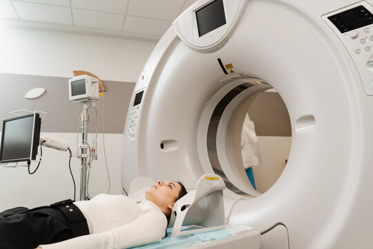 Girl patient is doing computed tomography x-ray examination of tumor in his head in a CT scan room. CT scan of brains of woman in medical clinic.