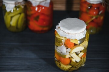 Jars of pickled vegetables on rustic wooden background