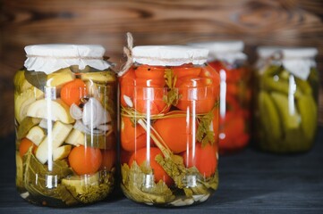 Jars of pickled vegetables on rustic wooden background